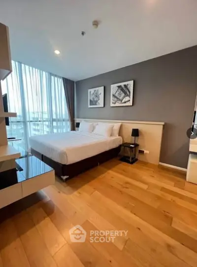 Modern bedroom with wooden flooring and large windows in a stylish apartment.