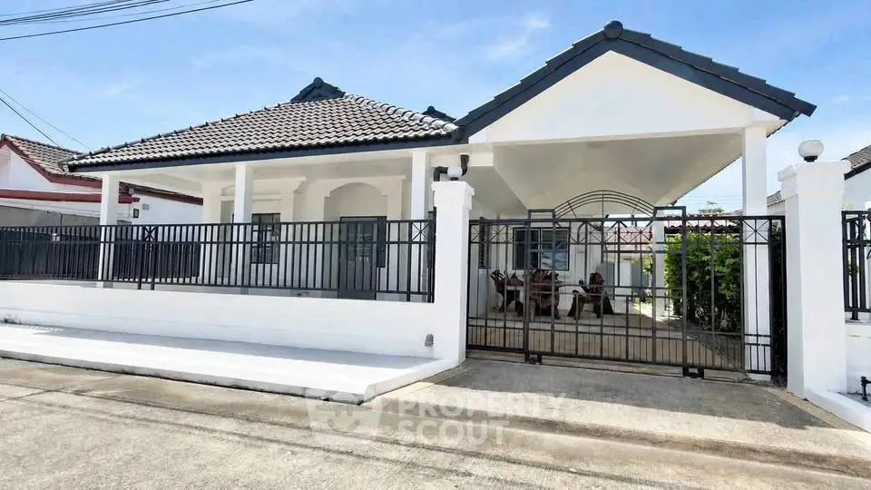 Charming single-story house with gated entrance and tiled roof in a serene neighborhood.