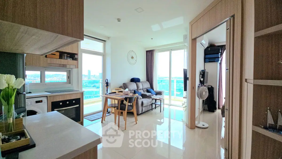 Modern open-layout living room with kitchen, featuring sleek furniture and large windows with city view.