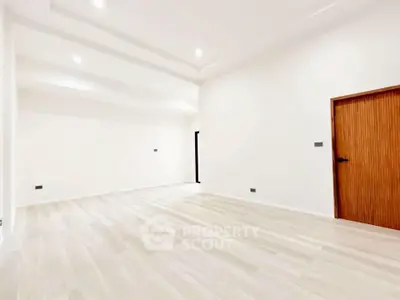 Spacious empty room with elegant wooden door and modern lighting, perfect for customization.