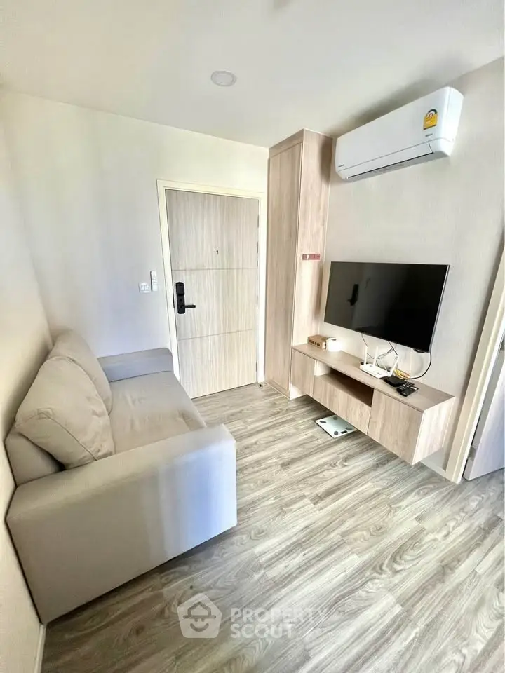 Modern living room with sleek design and air conditioning, featuring a cozy sofa and flat-screen TV.