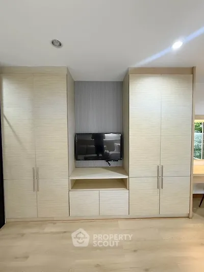 Modern living room with built-in storage and TV, featuring sleek design and ample natural light.