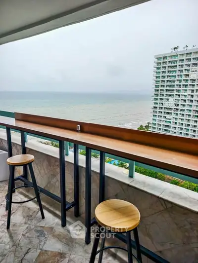 Stunning ocean view from a modern balcony with stylish seating, perfect for relaxation.