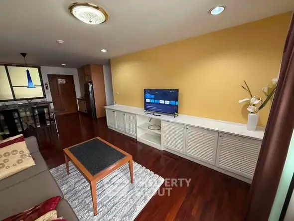 Spacious living room with modern decor and hardwood floors, featuring a flat-screen TV and stylish furniture.