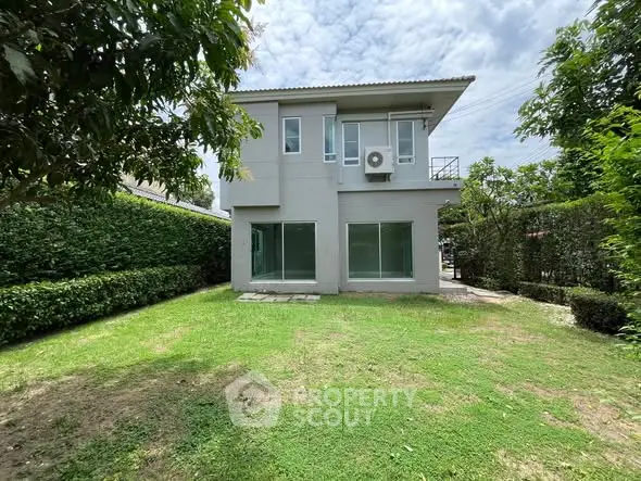 Modern two-story house with spacious green lawn and lush hedges