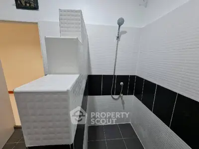Modern bathroom with sleek black and white tile design and shower area.