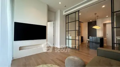 Modern living room with sleek design and open layout, featuring a large TV and stylish furnishings.