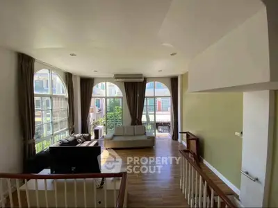Spacious living room with large windows and wooden flooring, perfect for natural light lovers.