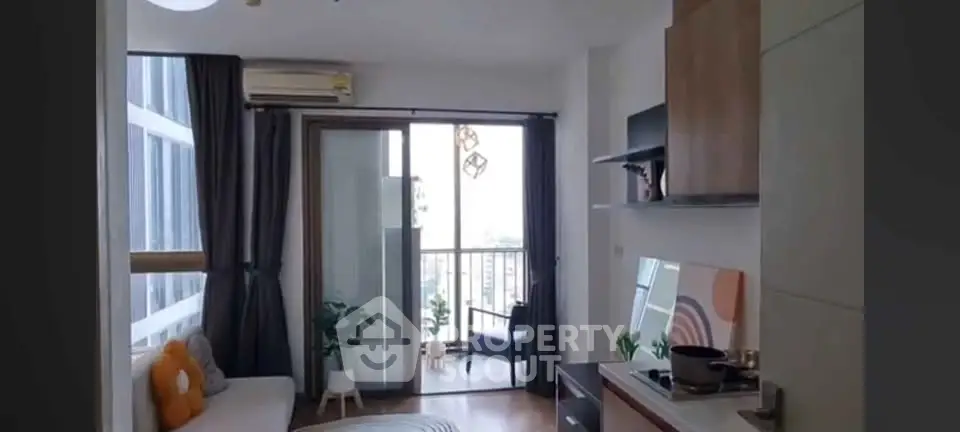 Modern apartment with open kitchen and cozy living area leading to a balcony with city view.