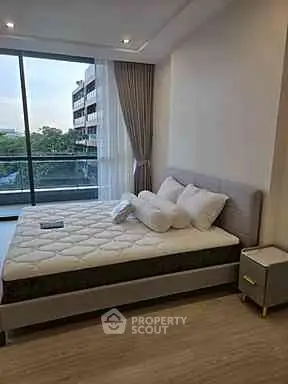 Spacious bedroom with large window and balcony view in modern apartment.