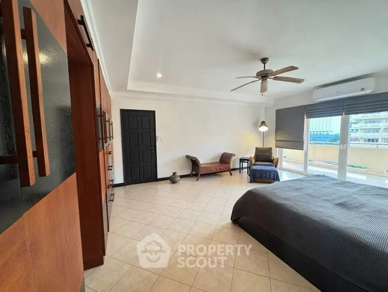 Spacious bedroom with modern decor and large windows offering city views.