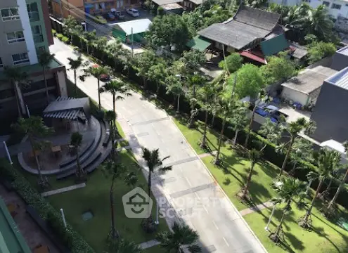Aerial view of a modern residential complex with lush greenery and a serene road.