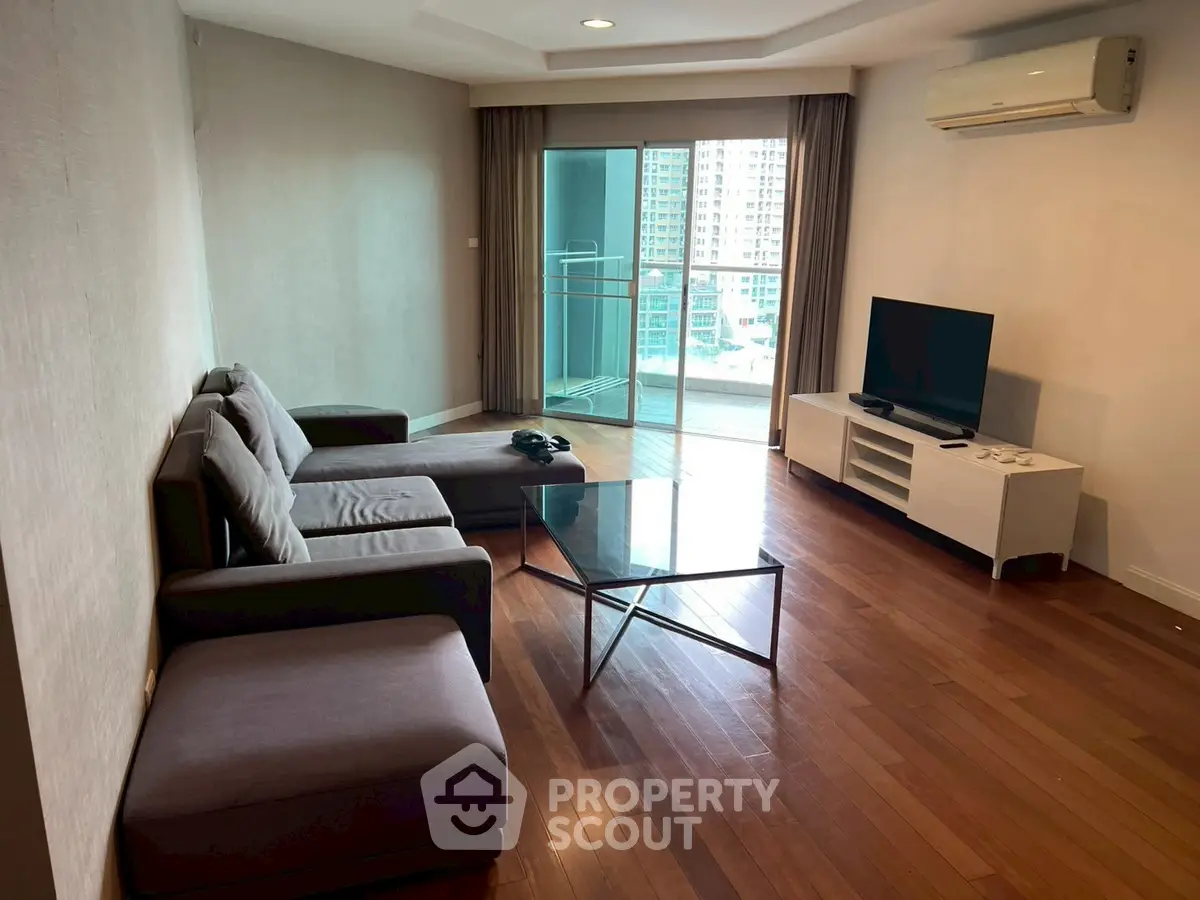 Spacious living room with modern furniture and balcony view in urban apartment.