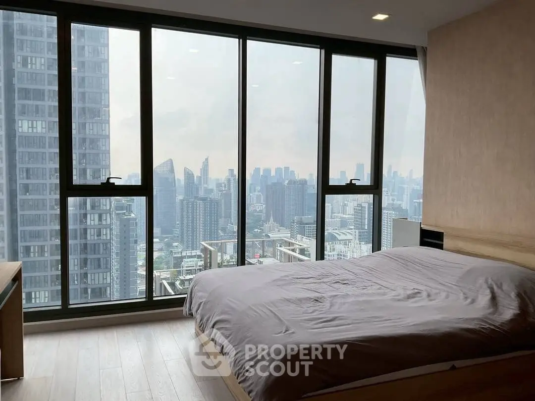 Luxurious bedroom with stunning city skyline view through floor-to-ceiling windows.