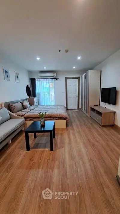 Modern bedroom with cozy decor and wooden flooring, featuring a TV and stylish furniture.