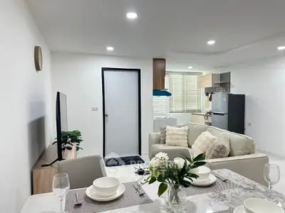 Modern open-layout living room with cozy seating and stylish kitchen area.