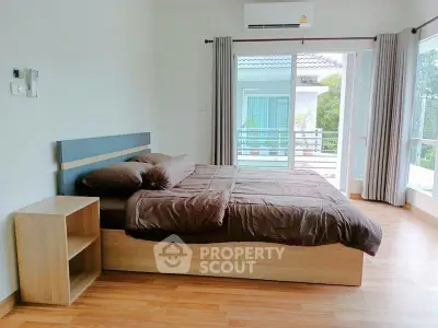 Spacious bedroom with modern decor and large windows offering natural light.