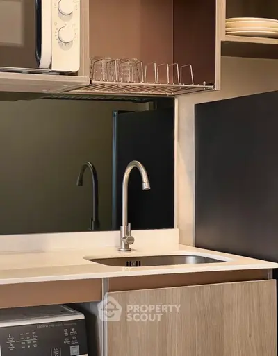 Modern kitchen with sleek design, featuring a compact sink and microwave, ideal for urban living.