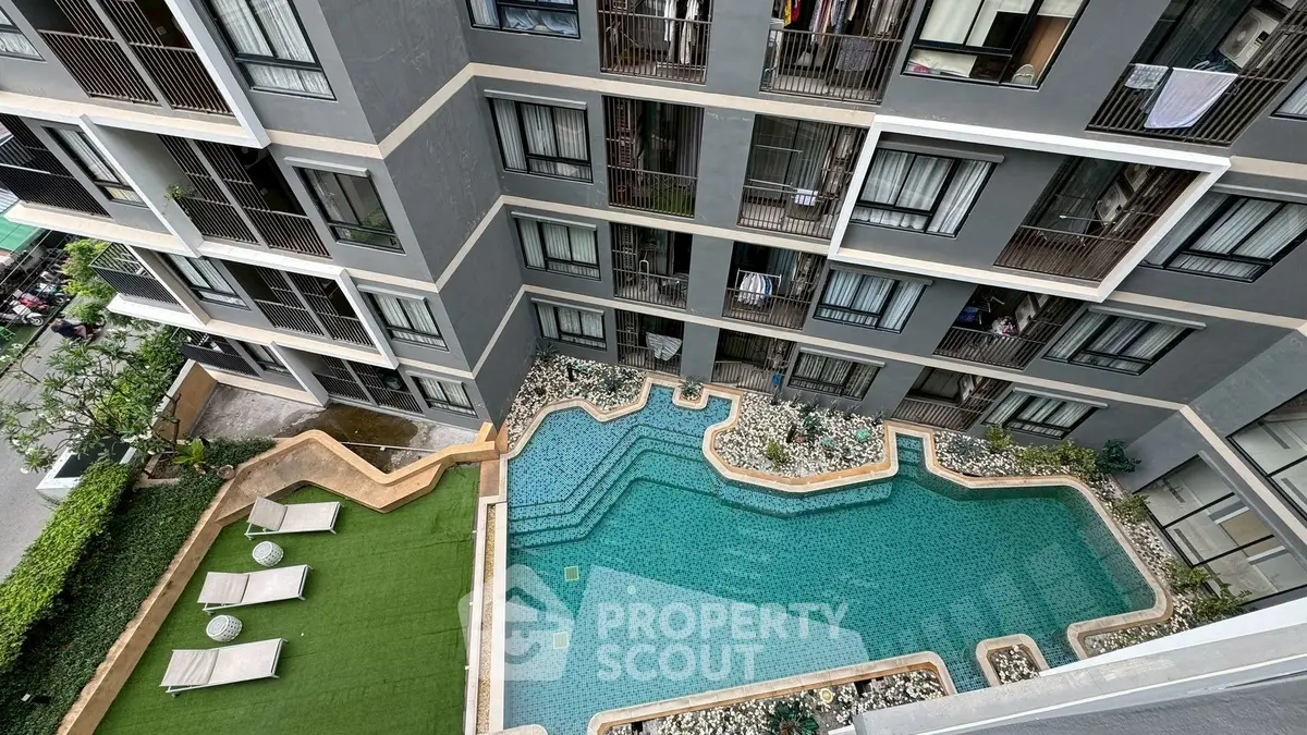Stunning aerial view of modern apartment complex with inviting pool and lush green area.