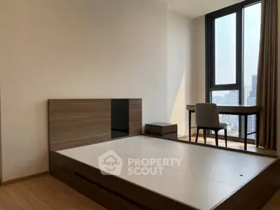 Modern bedroom with large window and study desk, offering city views and natural light.