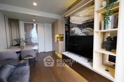 Modern living room with stylish decor and large TV, featuring elegant wooden flooring.
