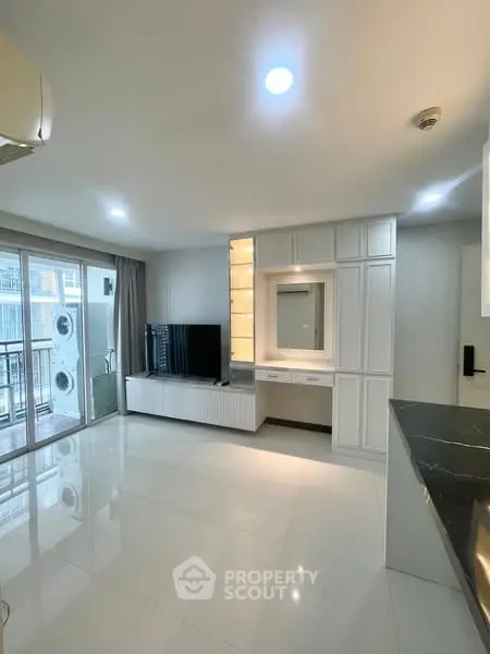 Spacious modern living room with sleek design and large windows opening to a balcony.