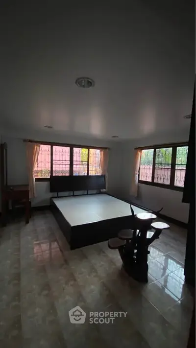 Spacious bedroom with large windows and minimalist furniture, offering ample natural light and serene ambiance.