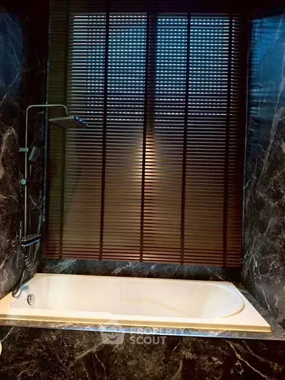 Luxurious marble bathroom with elegant bathtub and modern shower fixture.