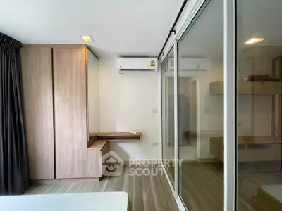 Modern bedroom with sleek wooden wardrobe and sliding glass doors in a stylish apartment.