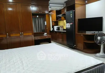 Spacious bedroom with wooden cabinetry and modern appliances in a cozy apartment.