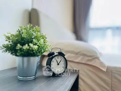 Cozy bedroom with stylish decor and classic alarm clock on bedside table.