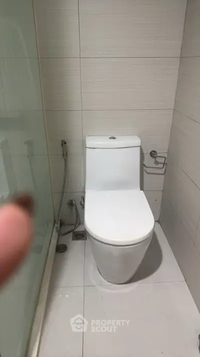 Modern bathroom with sleek toilet and glass shower enclosure, ideal for contemporary living spaces.