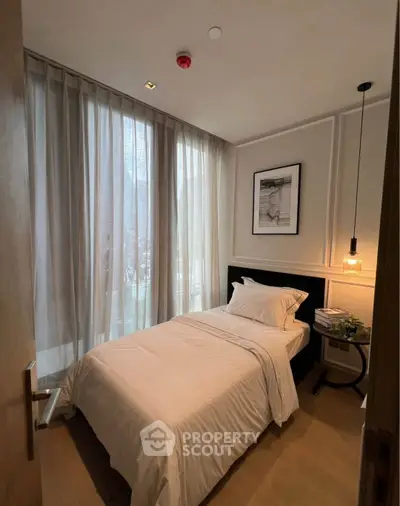 Cozy bedroom with elegant decor and natural light through sheer curtains.