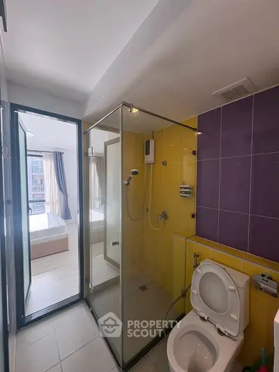 Modern bathroom with glass shower and view into a bright bedroom