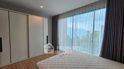 Spacious bedroom with large window and modern wardrobe in a stylish apartment.