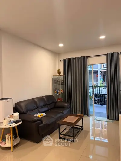 Modern living room with leather sofa and glass door leading to patio