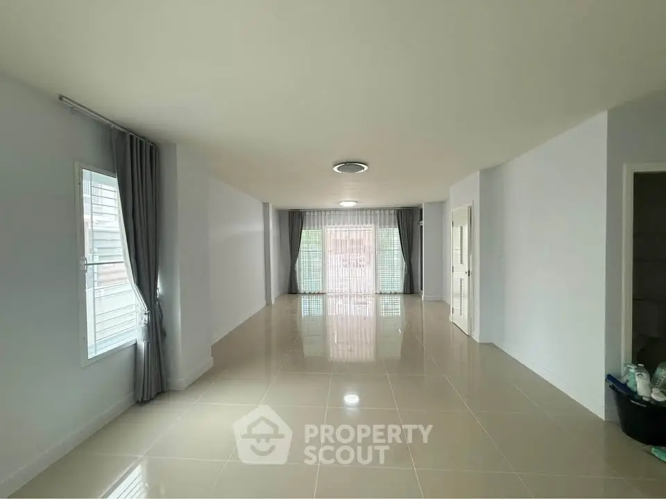 Spacious empty living room with large windows and modern tile flooring.