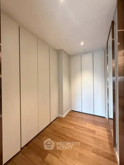 Spacious modern storage area with sleek white cabinets and wooden flooring, perfect for organizing essentials.