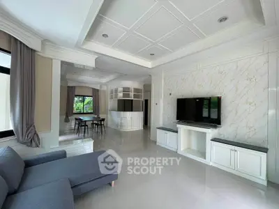 Spacious modern living room with elegant marble wall and large TV, featuring sleek furniture and open dining area.