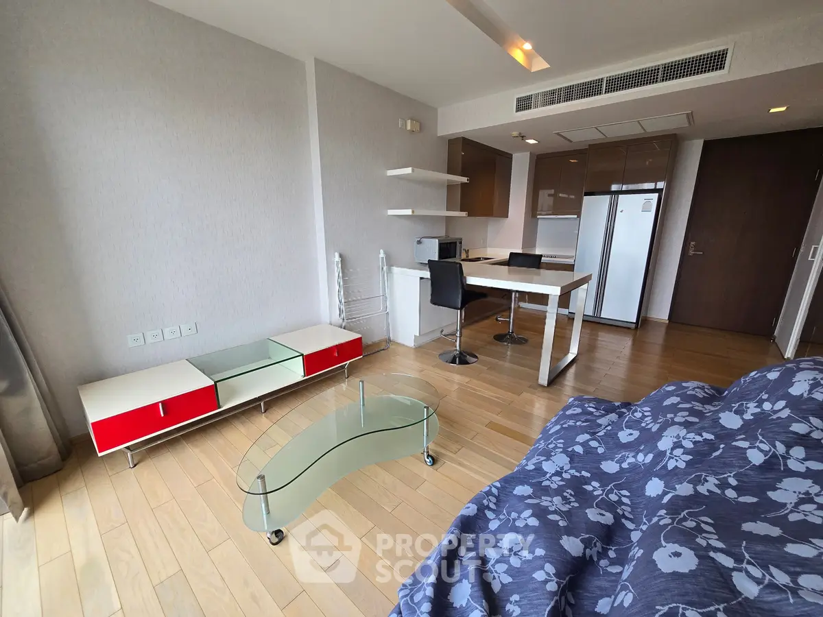 Modern open-layout living room with stylish furniture and kitchen area, featuring wooden flooring and contemporary design.