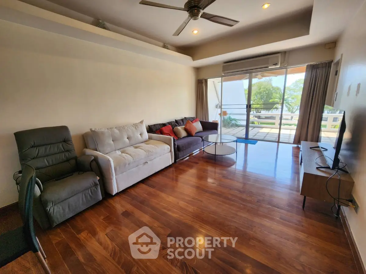 Spacious living room with hardwood floors and modern furniture, featuring a large window with a scenic view.