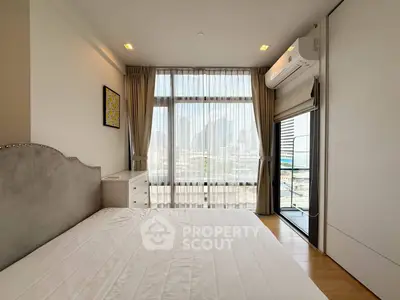 Modern bedroom with large window and city view, featuring air conditioning and elegant decor.