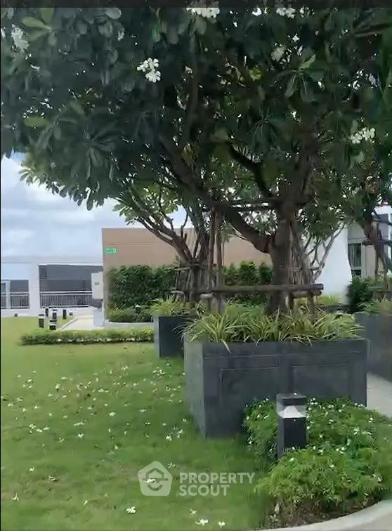 Lush garden area with trees and manicured lawn in a modern residential complex.