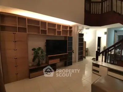 Spacious living room with modern entertainment center and elegant staircase