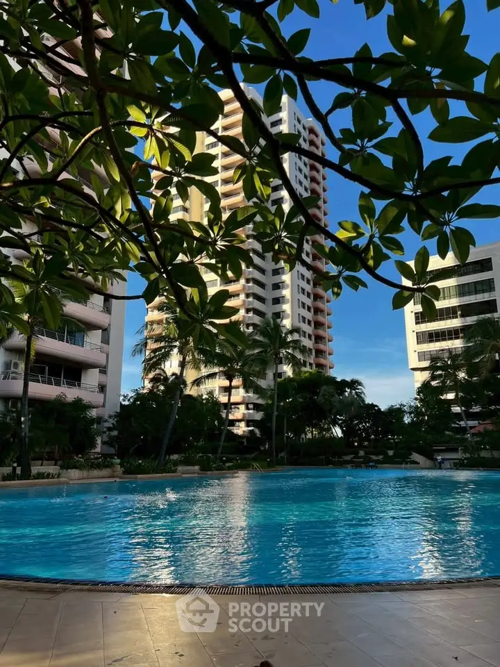 Luxurious residential building with a stunning pool and lush greenery, perfect for urban living.