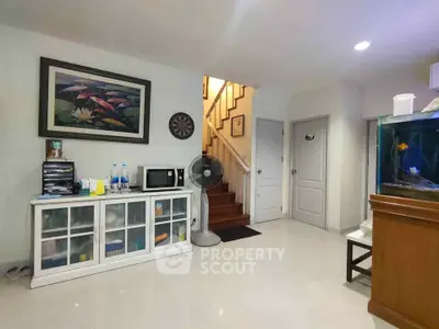 Cozy living area with modern decor and staircase, featuring a fish tank and wall art.