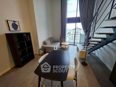 Modern loft apartment with high ceilings and city view, featuring stylish furniture and open staircase.