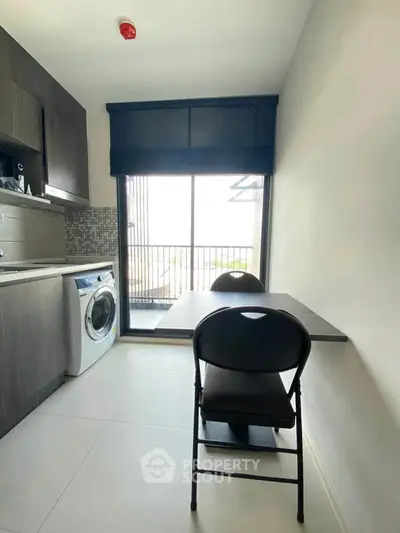 Modern kitchen with washing machine and dining area in compact apartment.