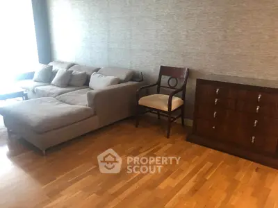 Spacious living room with elegant sofa and wooden furniture on polished hardwood floor.