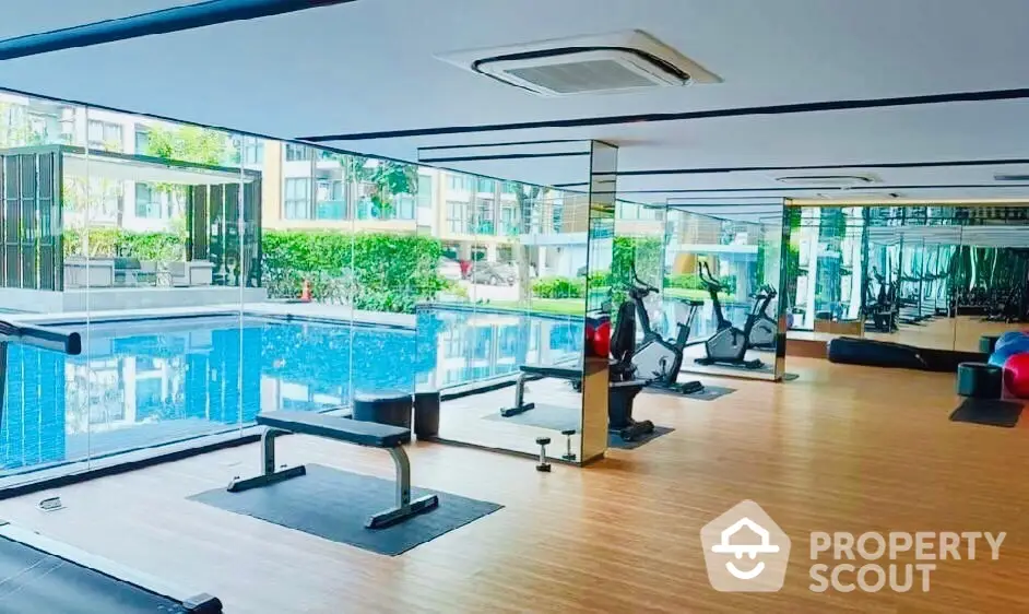 Luxurious condo gym with pool view and modern fitness equipment